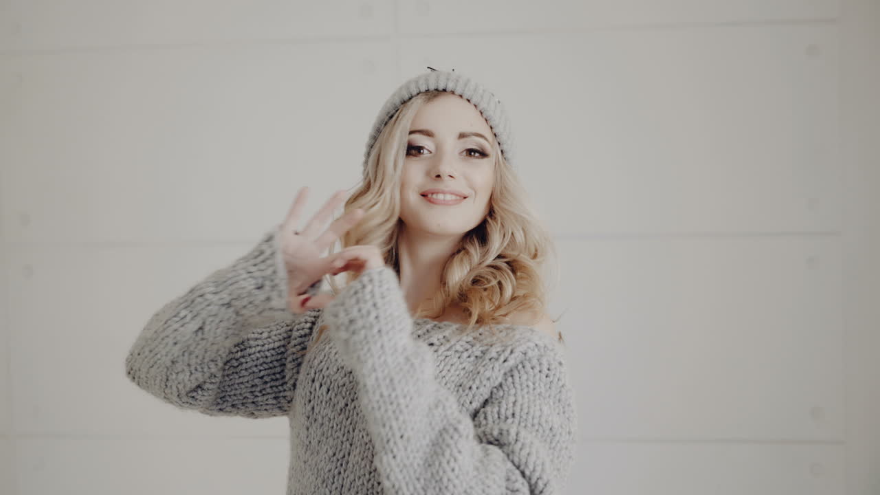 Happy girl in a knitted hat shows the heart. Valentine's Day.