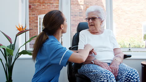 Senior-Woman-Sitting-In-Motorized-Wheelchair-Talking-With-Nurse-In-Retirement-Home