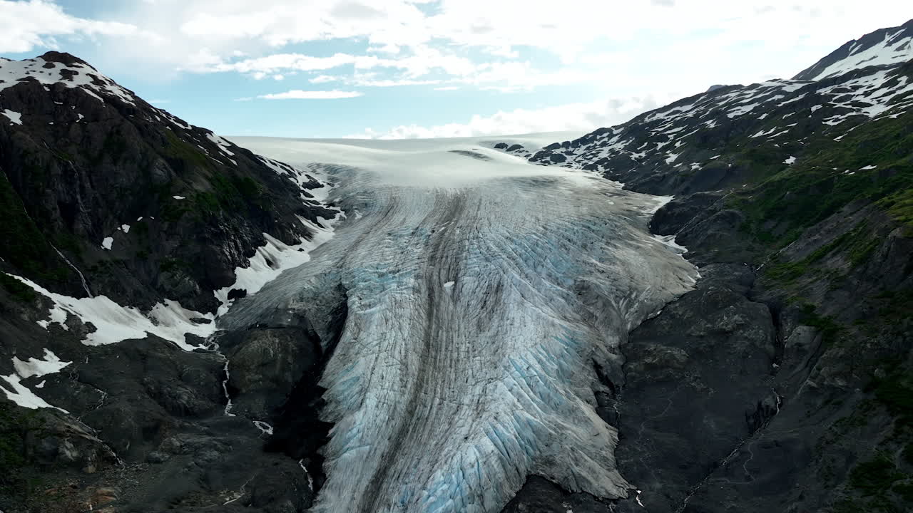 Black rocks with iceberg covering the gulch. Approaching the ridged layer of ice in the mountains of Alaska