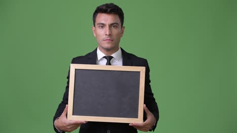 young handsome hispanic businessman against green background