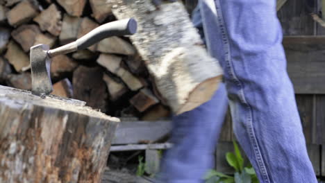 Man Walks Behind a Hatchet on a Stump to Set Logs on a Stack