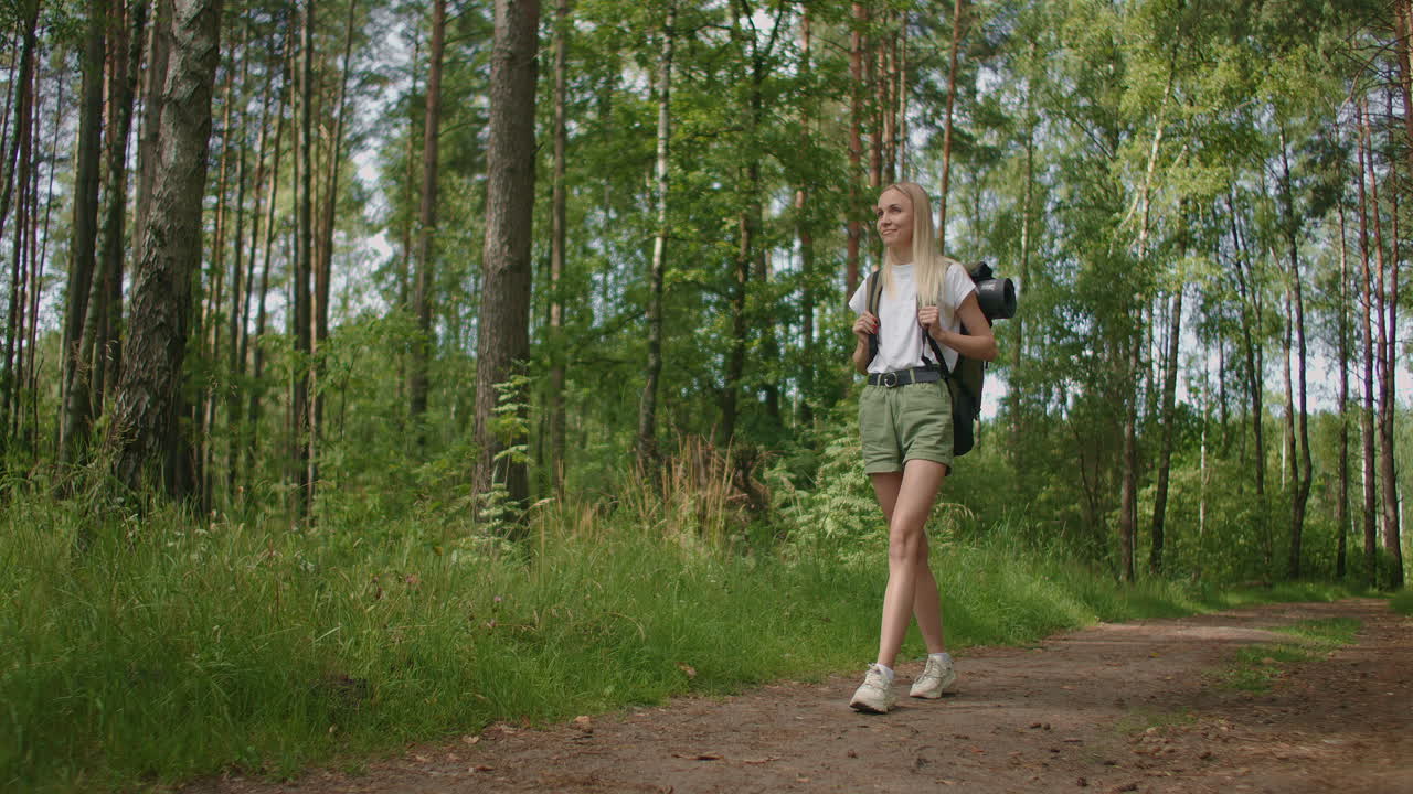General plan: Traveling Happy Caucasian blonde woman with backpack walking on path the tropical forest