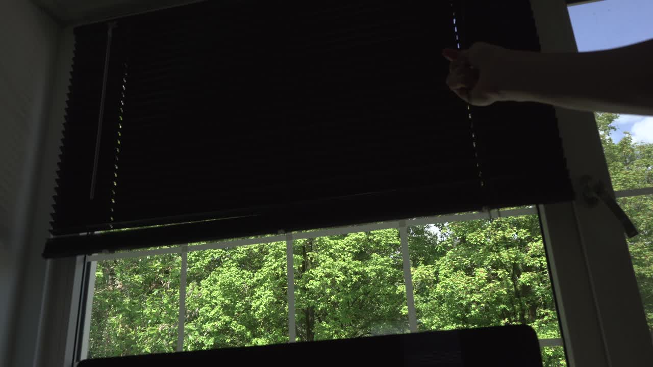Close up of guy closing the blinds of his home office