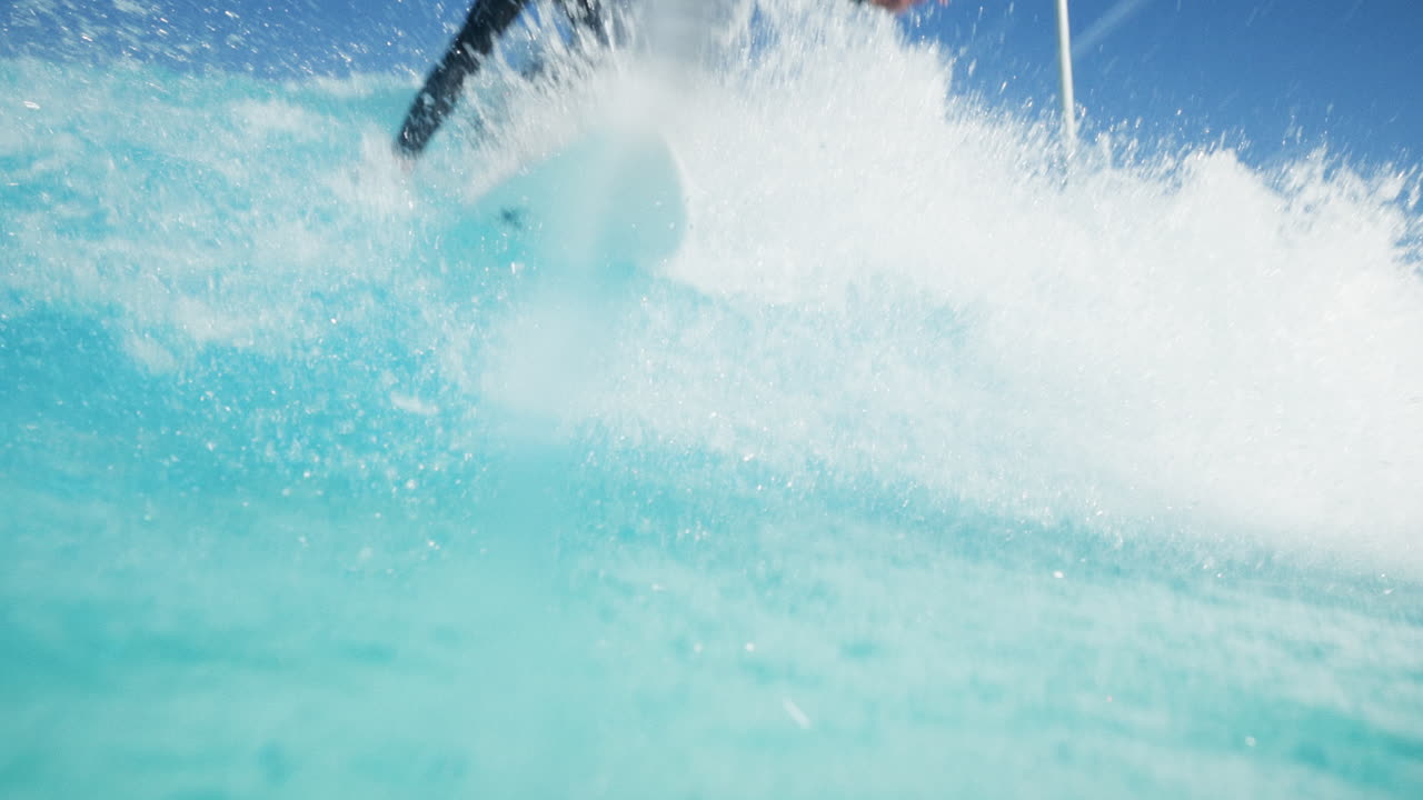 Surf de alto rendimiento en una moderna piscina de olas en un día soleado con agua cristalina. Giros potentes, tubos y rociones enmarcados por los Alpes suizos, creando un entorno de surf alpino único.