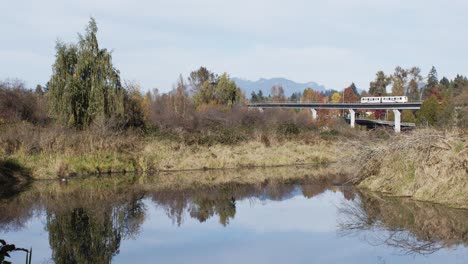 lake-with-reflection,-sky-train-passing-behind