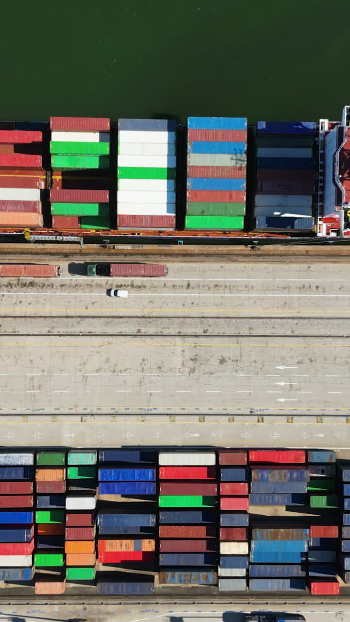 Vertical drone shot above containers and ships at a large shipward, sunny day