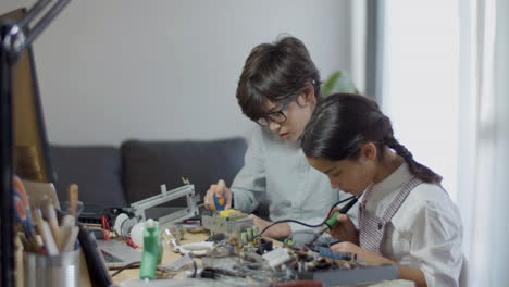 Dos-Niños-Haciendo-Un-Proyecto-De-Escuela-Electrónica-En-Casa-Durante-El-Día