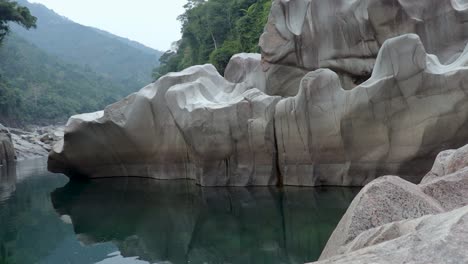 young man sitting at the natural formed white stone with river water video taken at cillian wah umsong dawki meghalaya india