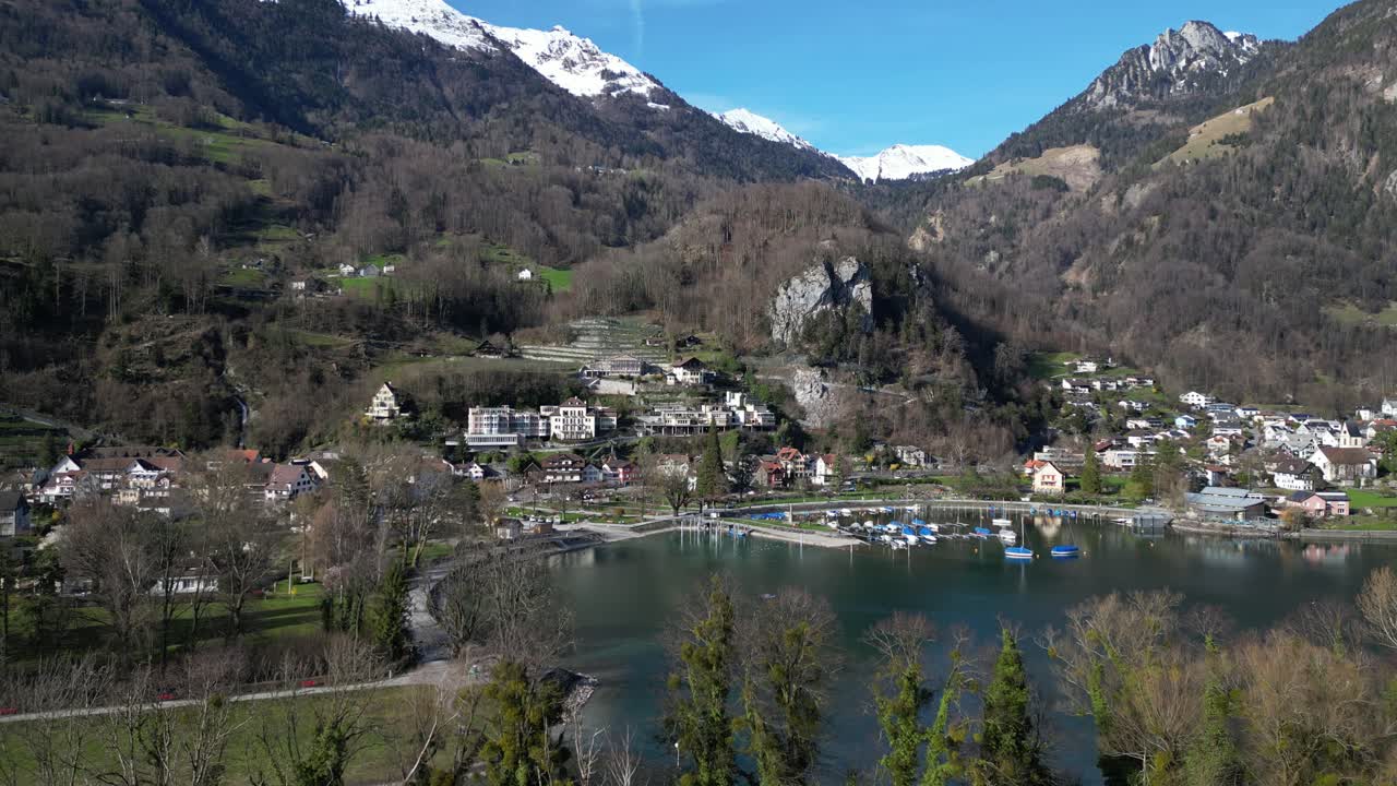 clip de avión no tripulado de un pueblo suizo tradicional en la orilla del lago walensee, rodeado de montañas cubiertas de nieve