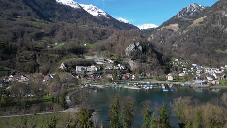 clip de avión no tripulado de un pueblo suizo tradicional en la orilla del lago walensee, rodeado de montañas cubiertas de nieve