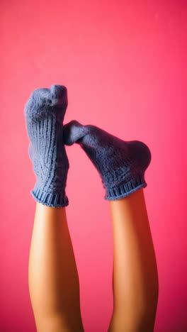 legs with blue socks against a vibrant pink background