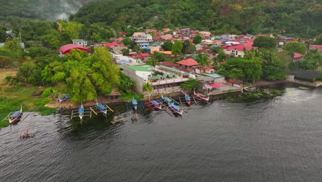 aerial orbit shot of asian neighborhood with traditional boats at shore in tropical area of philippines