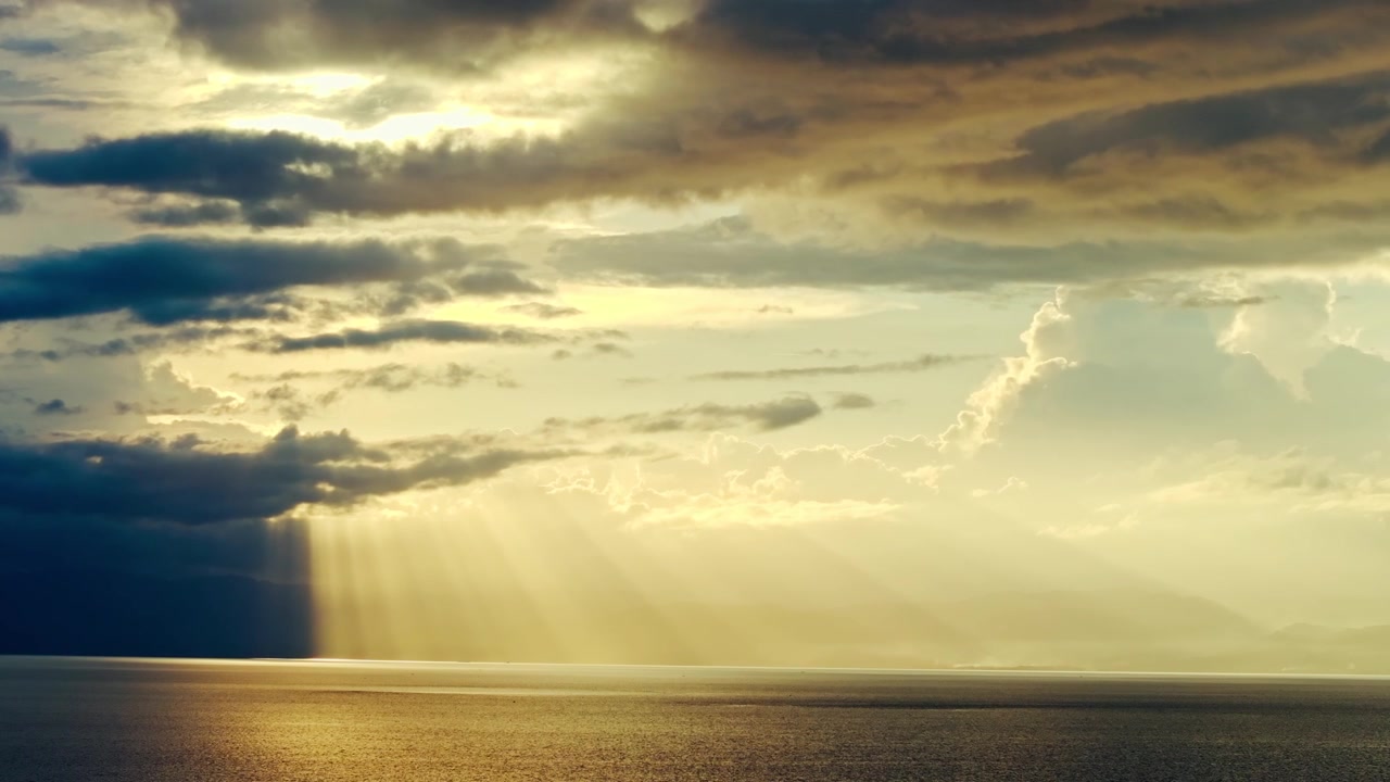 Divine light pierces dark clouds above calm sea horizon, Philippines aerial view