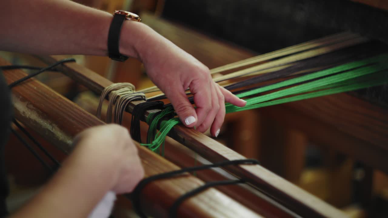 Woman ties knots and smoothes out yarn preparing hand weaving on loom