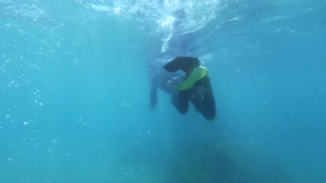 a scuba diver kicks up water causing bubbles in crystal clear blue water in maracajau in rio grande do norte, brazil