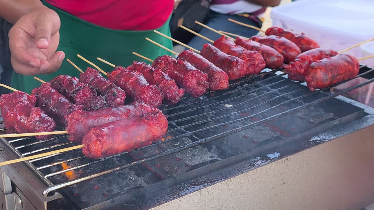 Tong Mo, or tung lamaow, a seasoned Cambodian-Cham beef sausage, sizzles over hot coals. This traditional minced meat sausage is being grilled for a savory flavor