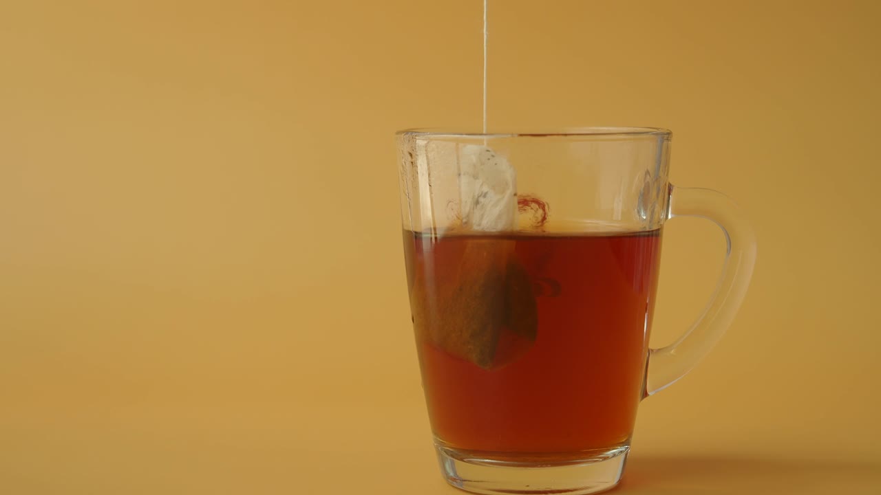 primer plano de una bolsa de té sumergida en una taza clara de té caliente