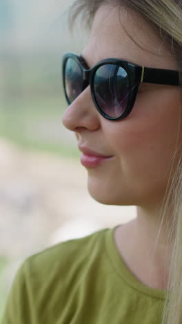 positiva mujer de cabello largo con gafas de sol negras mira con interés en la cabina en movimiento de poma ascensor en la estación de montaña primer plano en cámara lenta