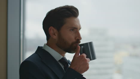 manager drinking coffee office looking at window admiring city view close up.