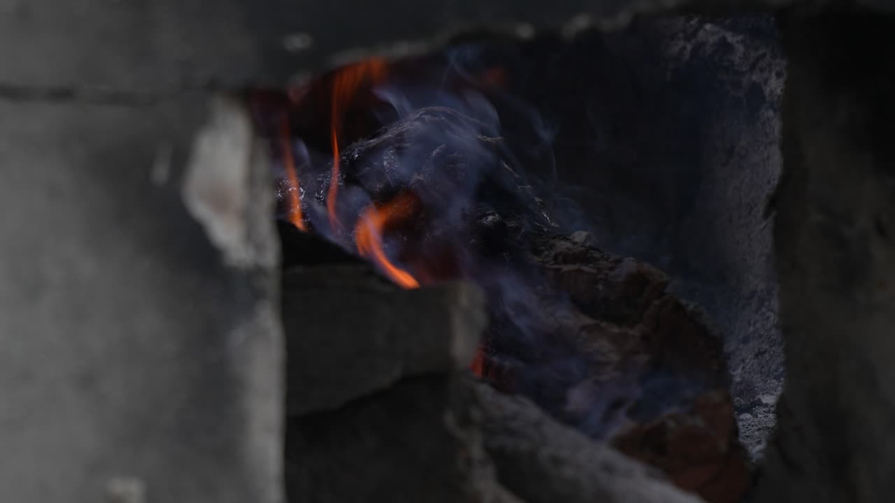 Detailansicht von Feuer, das in einem rustikalen traditionellen Ziegelofen brennt.