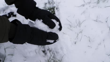 Tracking-shot-of-person-forming-a-snowball-during-cold-frozen-winter-day-in-the-mountains