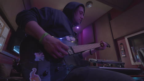 stationary shot of a guiatrist playing a song on a six string electric guitar while in a recording studio