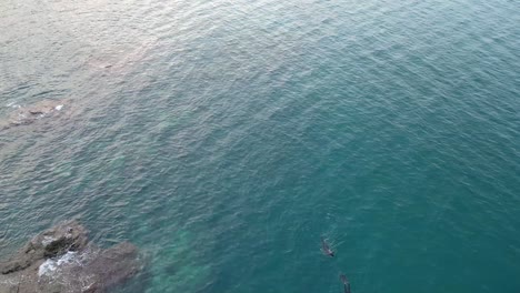 Aerial-view-of-two-divers-plunge-into-the-sea's-depths