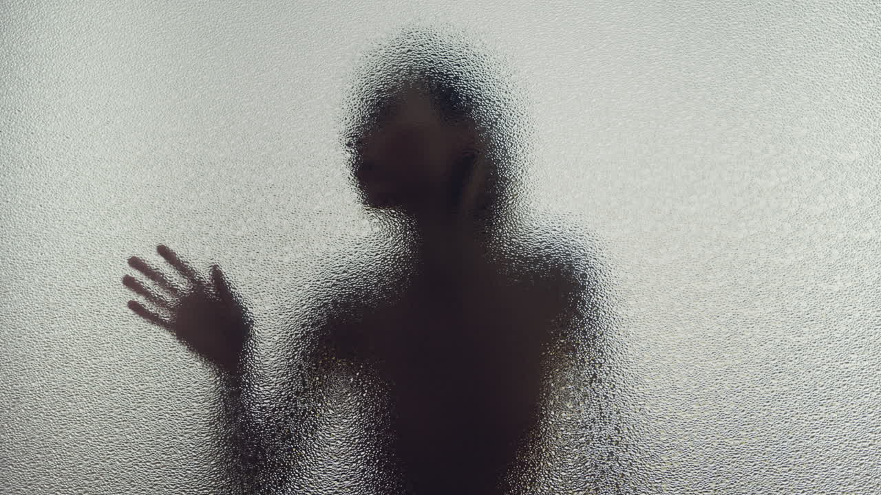 A female silhouette behind the frosted glass moves slowly