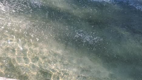 gotas de agua lloviznan por la textura ondulada de la superficie del agua ondulada dentro de la fuente