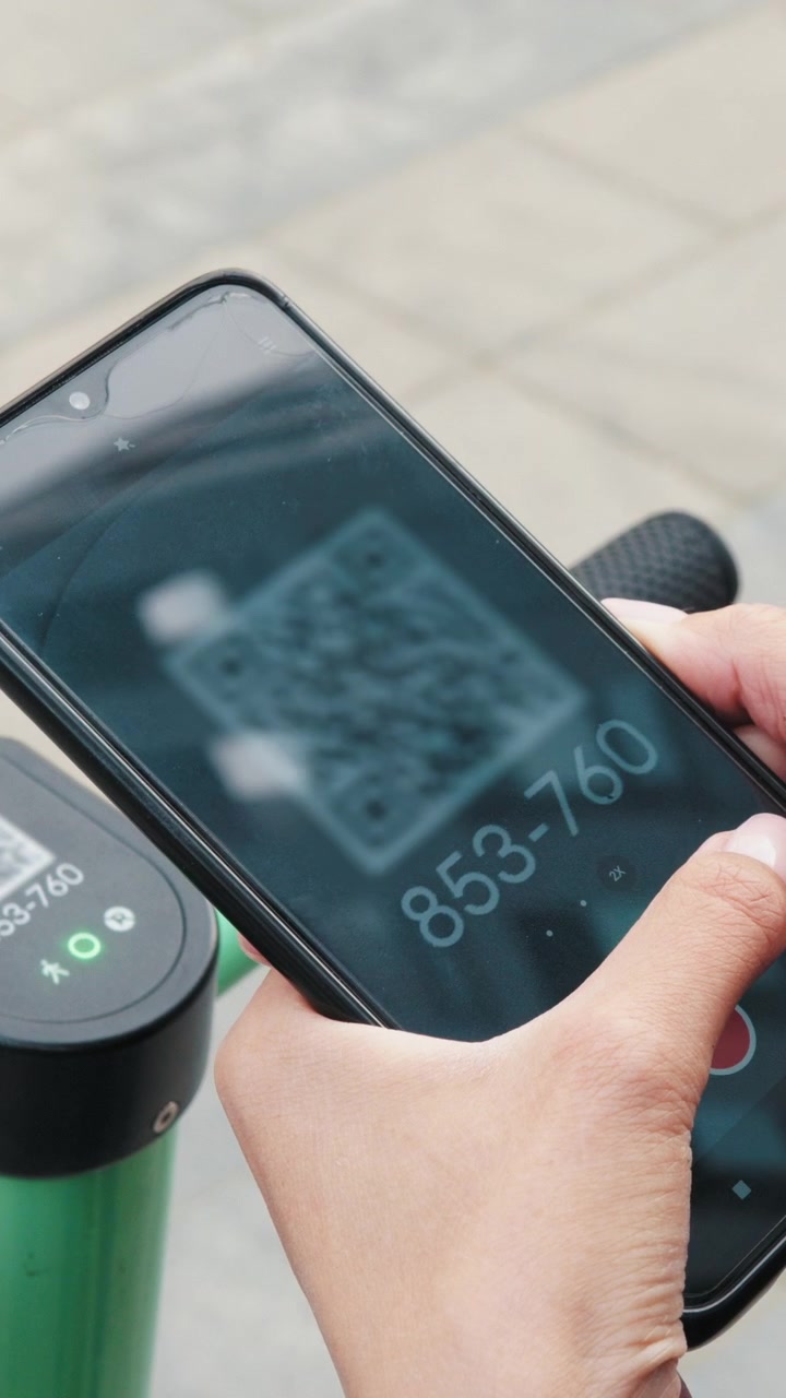 Una persona scansiona un codice QR con il proprio telefono, probabilmente per sbloccare o interagire con un dispositivo vicino.