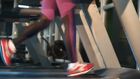 woman in purple leggings is running on a modern treadmill in fitness club. running legs in sneakers on simulator in gym. cardio training. close-up. sport for slender figure.