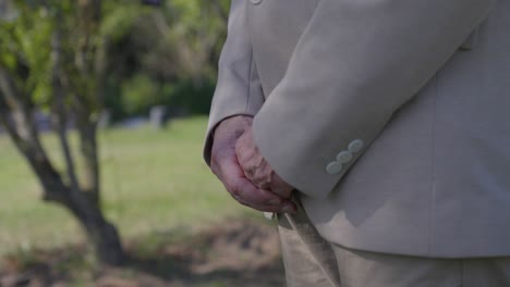 a person in a suit stands with hands clasped in front of them, observing a wedding ceremony