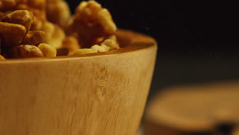 close up shot of walnuts dropping into wooden bowl against black studio background shot in slow motion 1