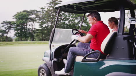 mature couple playing golf driving buggy along course to green