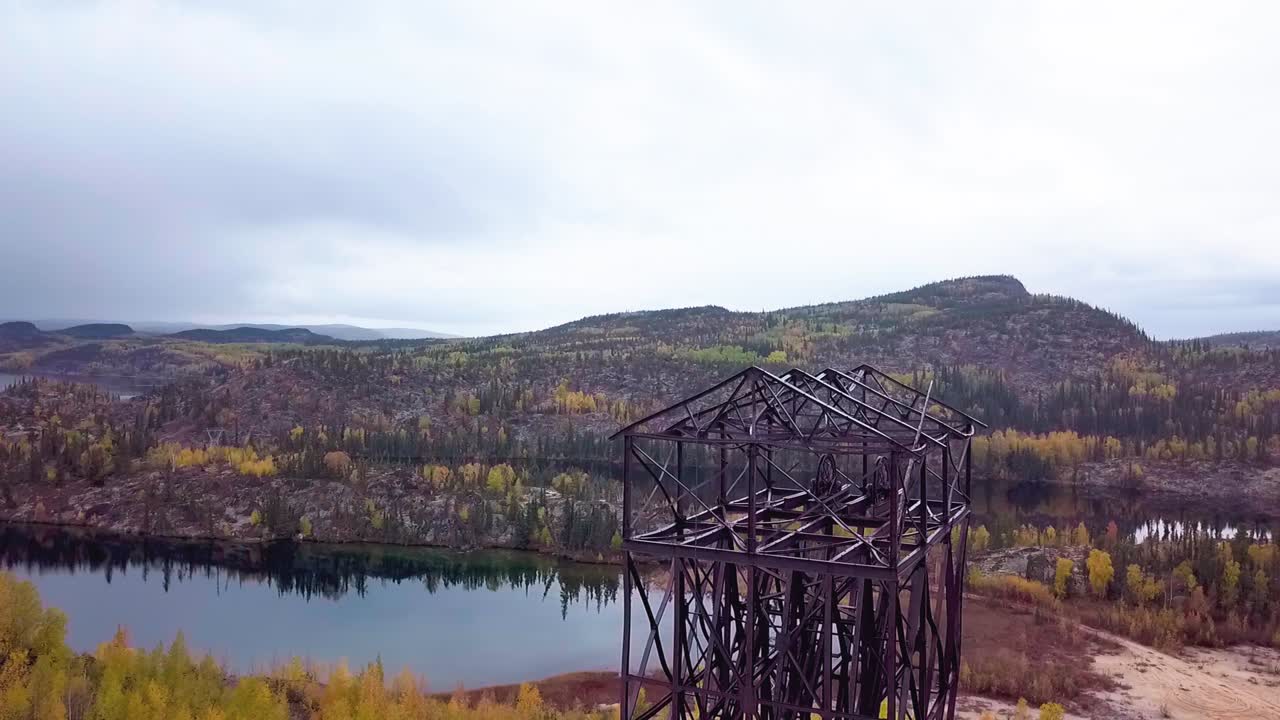 pedestal descendente aéreo en cámara lenta de un marco de cabeza de mina abandonada en el bosque boreal en otoño
