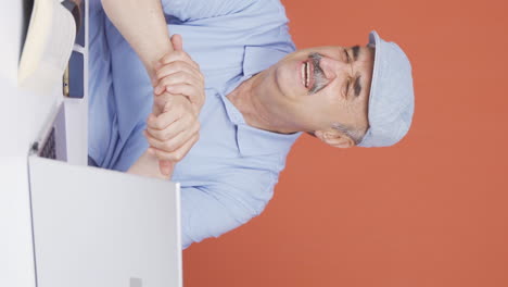 el video vertical de la muñeca del anciano usando una computadora portátil duele.
