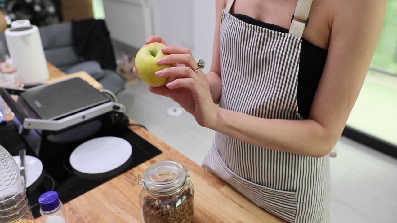 Woman holding an apple in the kitchen
