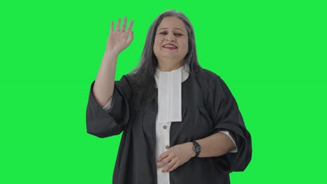 feliz abogada india senior diciendo hola y agitando la pantalla verde