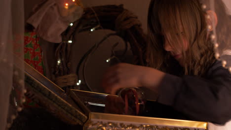 beautiful closeup of young girl opening decorated box with christmas ball and presents inside