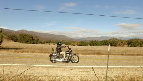 aerial over a man riding a harley davidson motorcycle through the countryside