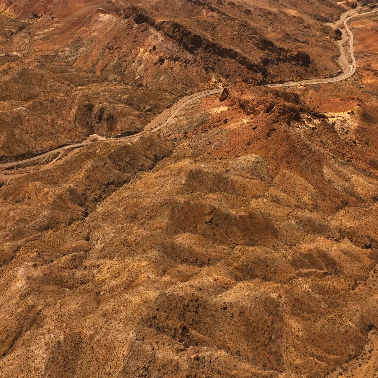 Brown dry landscape of Mojave desert. Rocky landscape with a highway in the middle. Top view