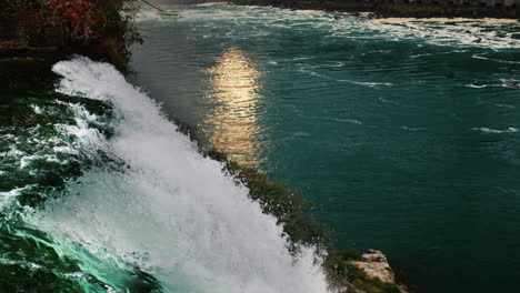 sunset at niagara falls. the sun reflects in the river, in the foreground there is a grandiose flow of water