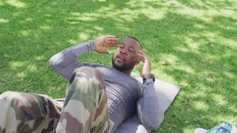 un soldado afroamericano haciendo ejercicios y abdominales en el jardín.