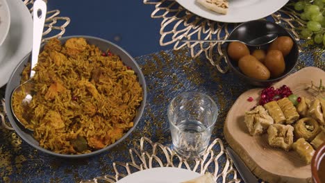 close up of muslim family sitting around table with food for meal celebrating eid being served 2