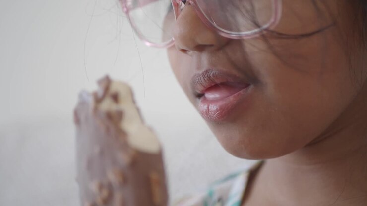 Ragazza che gusta un gelato al cioccolato e mandorle.