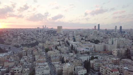 peaceful and quiet early morning aerial clip of amman jordan taken by a drone which slowly pans to the left for the newly-risen sun and a flock of birds passing by