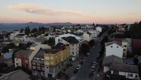 Aerial-view-of-street-with-passing-cars-and-residential-area-in-Patagonia,-South-America