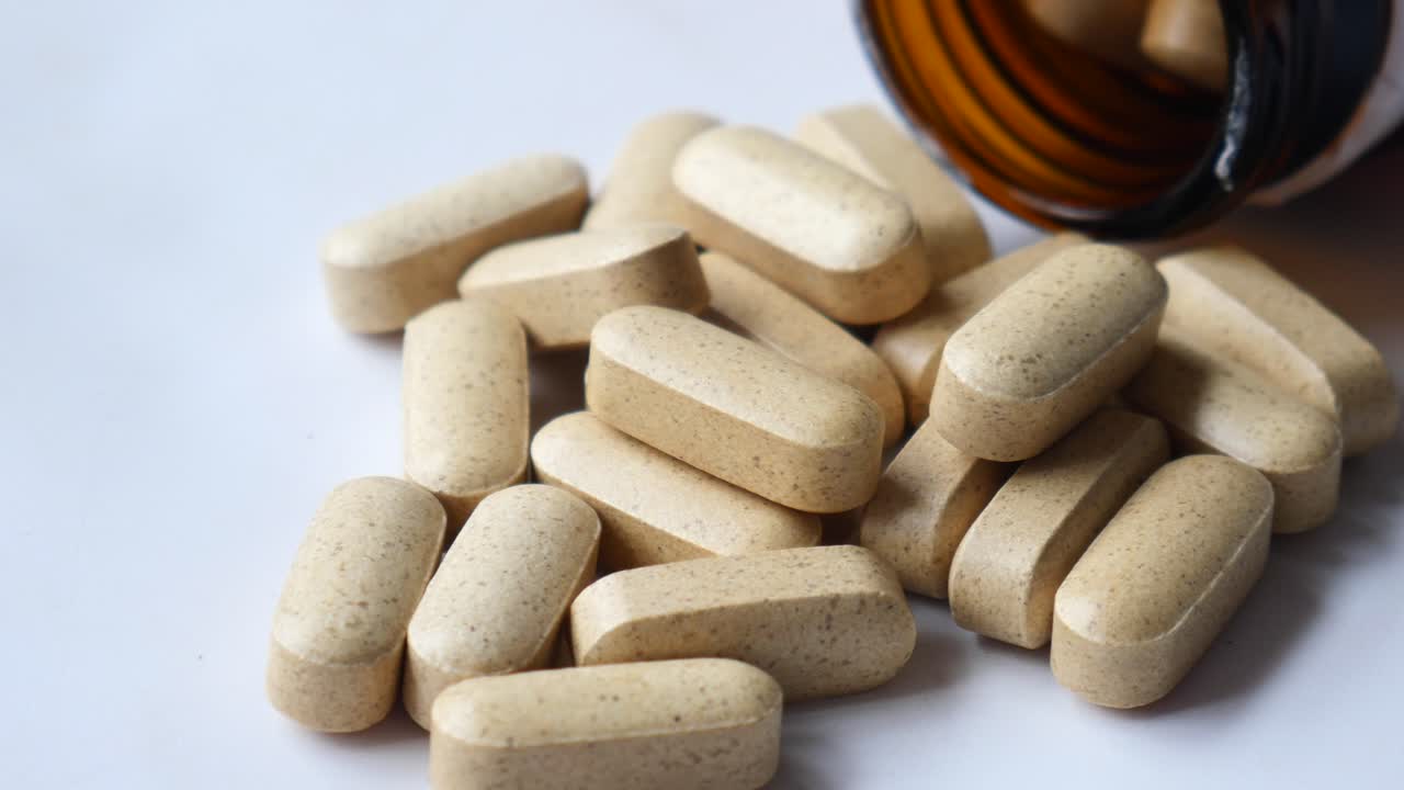 cerca de varias cápsulas de vitaminas derramadas de una botella de alta calidad 4k metraje