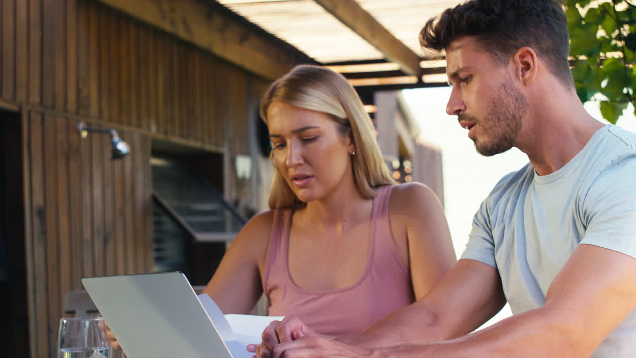 una pareja preocupada usando una computadora portátil en casa para comprobar las finanzas domésticas