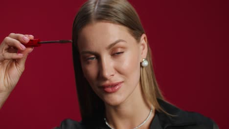 mujer aplicando máscara frente al fondo rojo